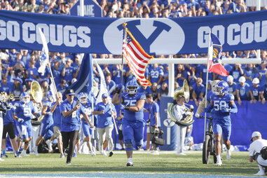 Sam Dawe #75 and Aisea Moa #58 of the Brigham Young Cougars carry the American flag and the Utah State flag as they lead the team onto the field before the start of their game against the Southern Illinois Salukis LaVell Edwards Stadium on August 31, 2024