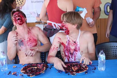 two young men covered in blueberries during a pie eating contest
