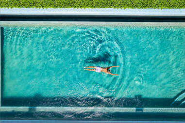 a person swimming in a pool in the sun