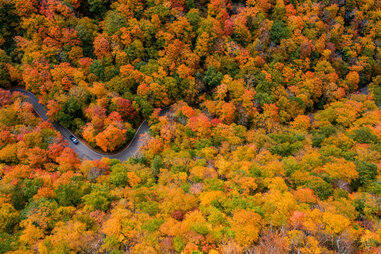 road through orange and green fall foliage in Smugglers' notch in Vermont