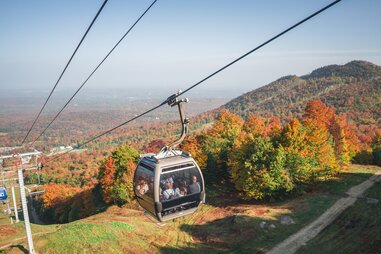 couple on ski lift hovering above fall foliage