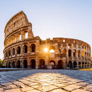 Sun shining through the arches of Coliseum at sunrise, Rome, Italy