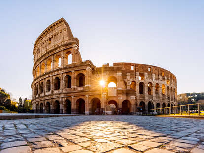 Sun shining through the arches of Coliseum at sunrise, Rome, Italy