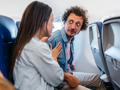 Young Woman Consoling Her Boyfriend Who Is Having A Panic Attack In An Airplane