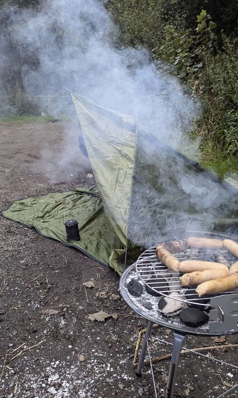 Sausages being cooked near a campsite