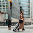 Young woman carrying luggage, walking on the high street in the city.