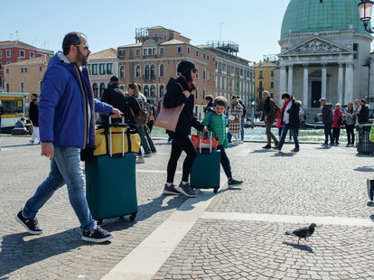 tourists walking through venice with suitcase