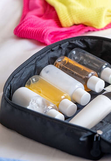 Travel cosmetics kit with bottles, pills and cosmetics on bed