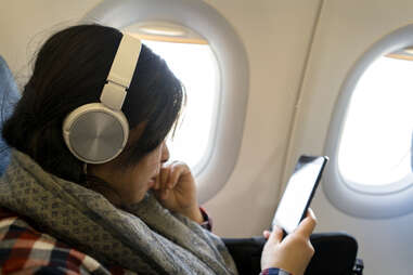 A girl reading smart phone on plane.