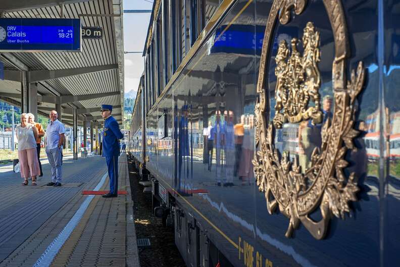 a man standing outside of a blue luxury train 