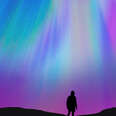 Silhouette of a guy with the beautiful colorful northern lights falling from the sky