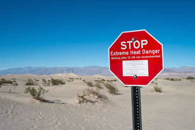 Red stop sign in Stove Pipe Dunes, Death Valley, showing the “extreme heat danger” sign.