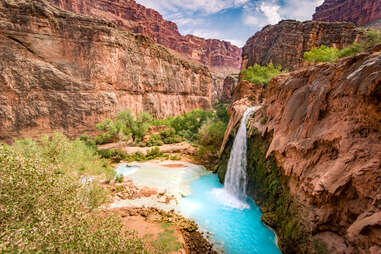 red rock and a waterfall into surreal light blue water; havasupai falls