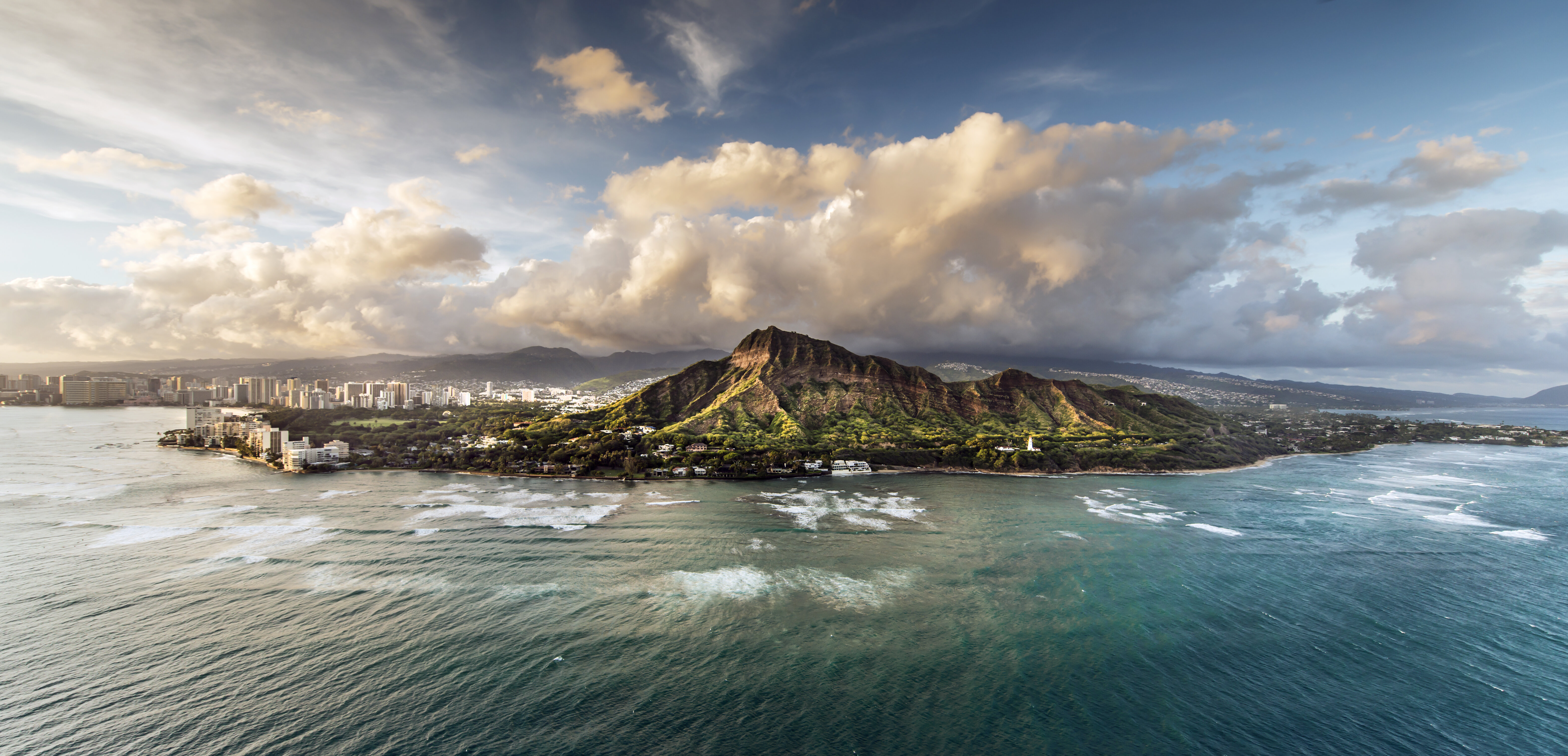 Aerial view of Hawaii, Honolulu and Diamond Head at sunset with the sea in the foreground. 