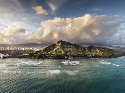 Aerial view of Hawaii, Honolulu and Diamond Head at sunset with the sea in the foreground.