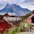 a rickety red mining town in front of a mountain