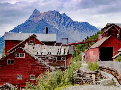 a rickety red mining town in front of a mountain