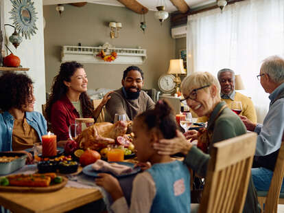 Happy multigeneration family gathering for Thanksgiving meal at dining table.