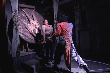 A scared woman standing in between a throwing knives circus act