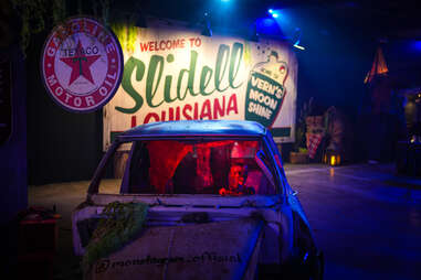 Skeleton driving a car in front of a sign that says Slidell, Louisiana