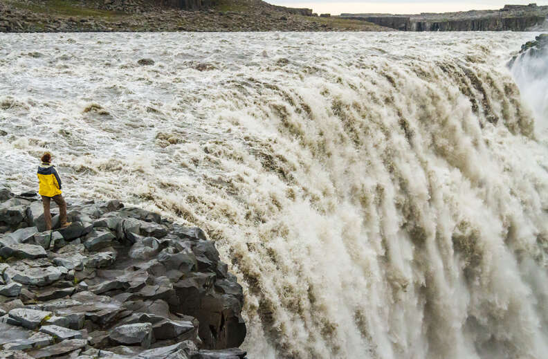 a person in a yellow jacket near Dettifoss waterfall, Jokulsargljufur National Park