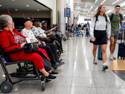 Travelers in wheelchairs wait near check-in desks at Hartsfield-Jackson Atlanta International Airport in Atlanta, Georgia.