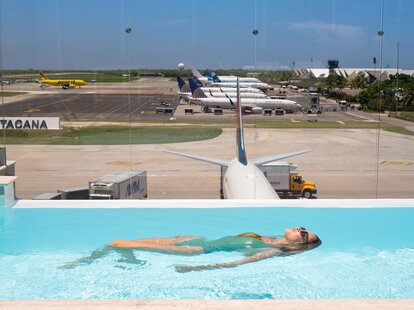 a woman in a pool floating with planes in the background