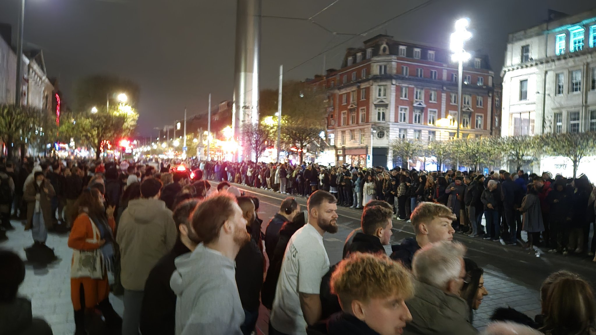 A photo of people waiting on an empty street for a parade that doesn't exist. 