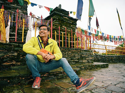 A man sitting at old stone ruins at Rabdentse ruins at Sikkim, wearing a fanny pack.