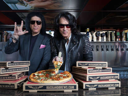 gene simmons of KISS posing with pizza boxes at Rock & Brews restaurant in LA