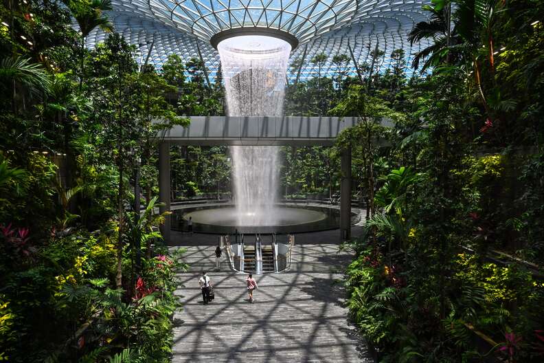 an indoor waterfall at an airport, with people 