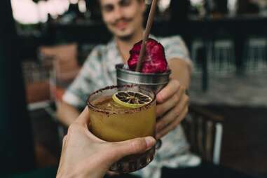 close up of hand holding cocktail in a coconut