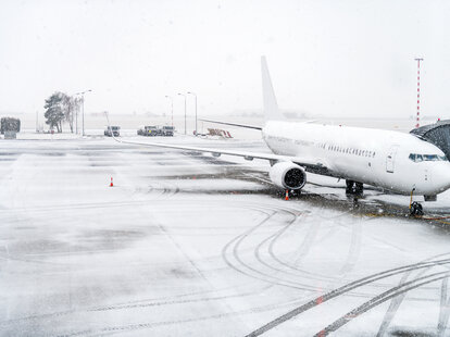 Horizontal color image of airplane during snowstorm on a runway.