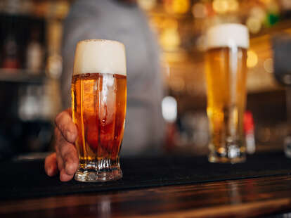 Glass filled with fresh light beer on bar counter.