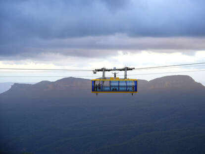 man standing on top of a cable car in the mountains of katoomba