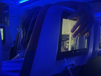 A hand covering the in-flight entertainment screen on a Delta flight