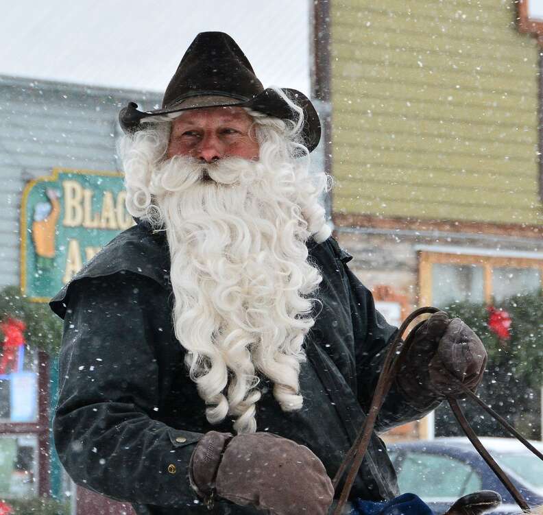 a man in a black cowboy hat on a horse in the snow in montana 