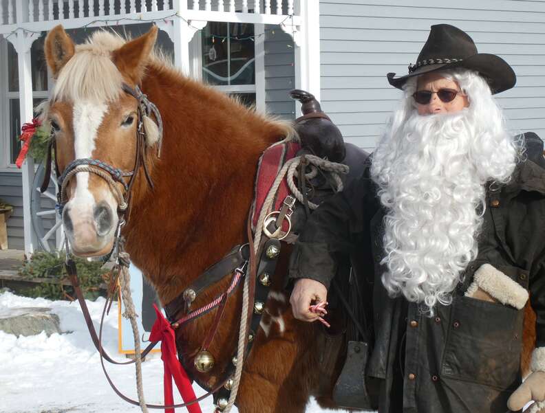 a cowboy Santa Claus in black, with his decorated horse 