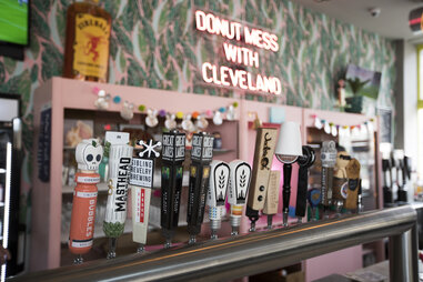 a row of colorful tap handles and neon signage inside brewnuts craft beer bar in cleveland