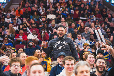 man drinking a beer wearing a cleveland themed shirt in a crowd inside rocket arena in cleveland, ohio