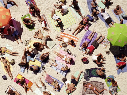 Crowd of people sunbathing on beach, over head view
