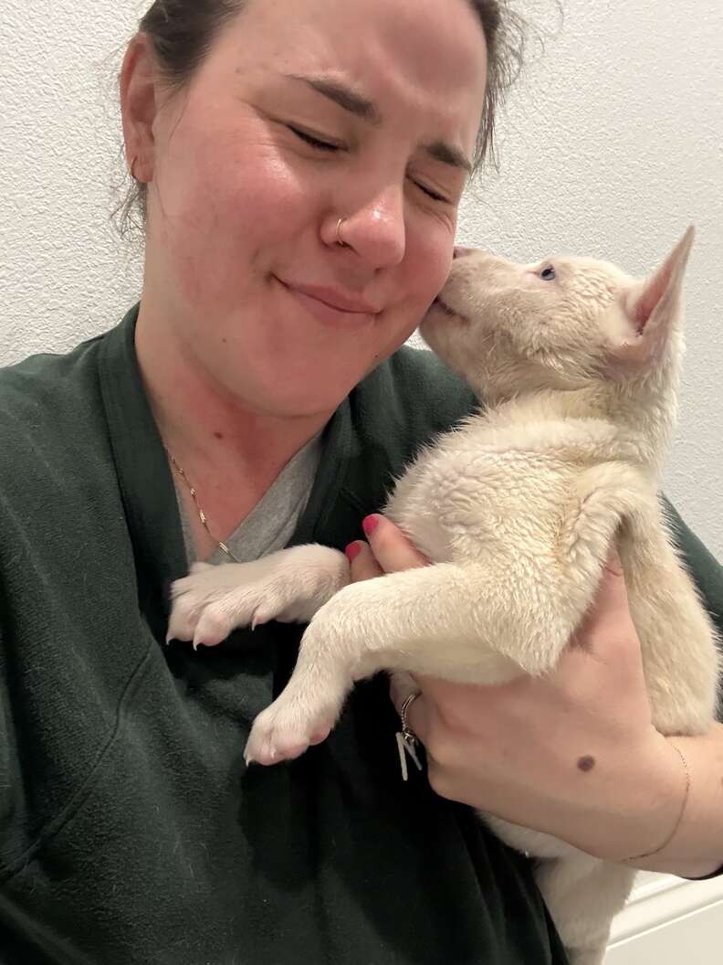 Woman holding up white dog