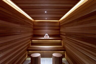 interior of a sauna with stripes of dark and blonde wood and two stools at the spa at the joule in dallas, texas