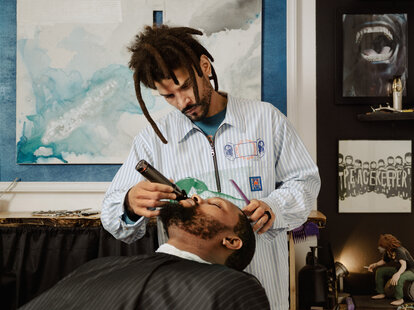stylish barber cuts hair in front of eclectic art as part of a new Airbnb Service