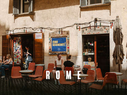 A patio restaurant with a handful of diners sitting in orange chairs.