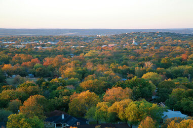 an aerial shot of the texas hill country landscape with fall colors showing in the trees