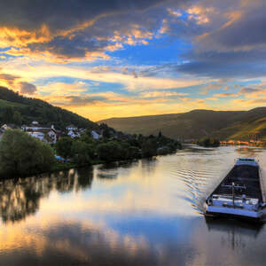 Beautiful vibrant sunset view of the river Moselle at the small wine growing town Zell (an der Mosel) with hills full of grape vines with a barge on the river
