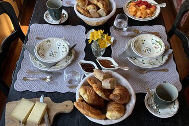 a breakfast spread of bread, cheese, fruit, and pastries on a barge cruise in France