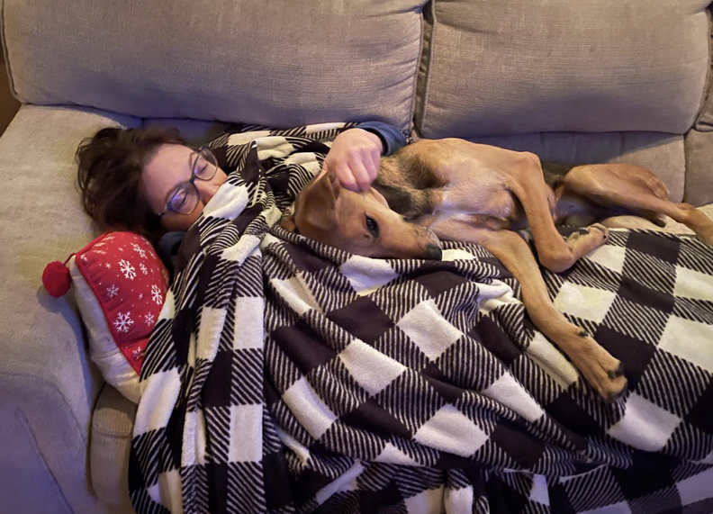 woman cuddling with dog on couch 