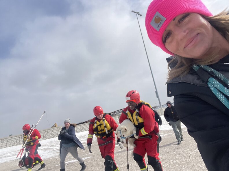 A rescue team carries a hypothermic dog across a parking lot.